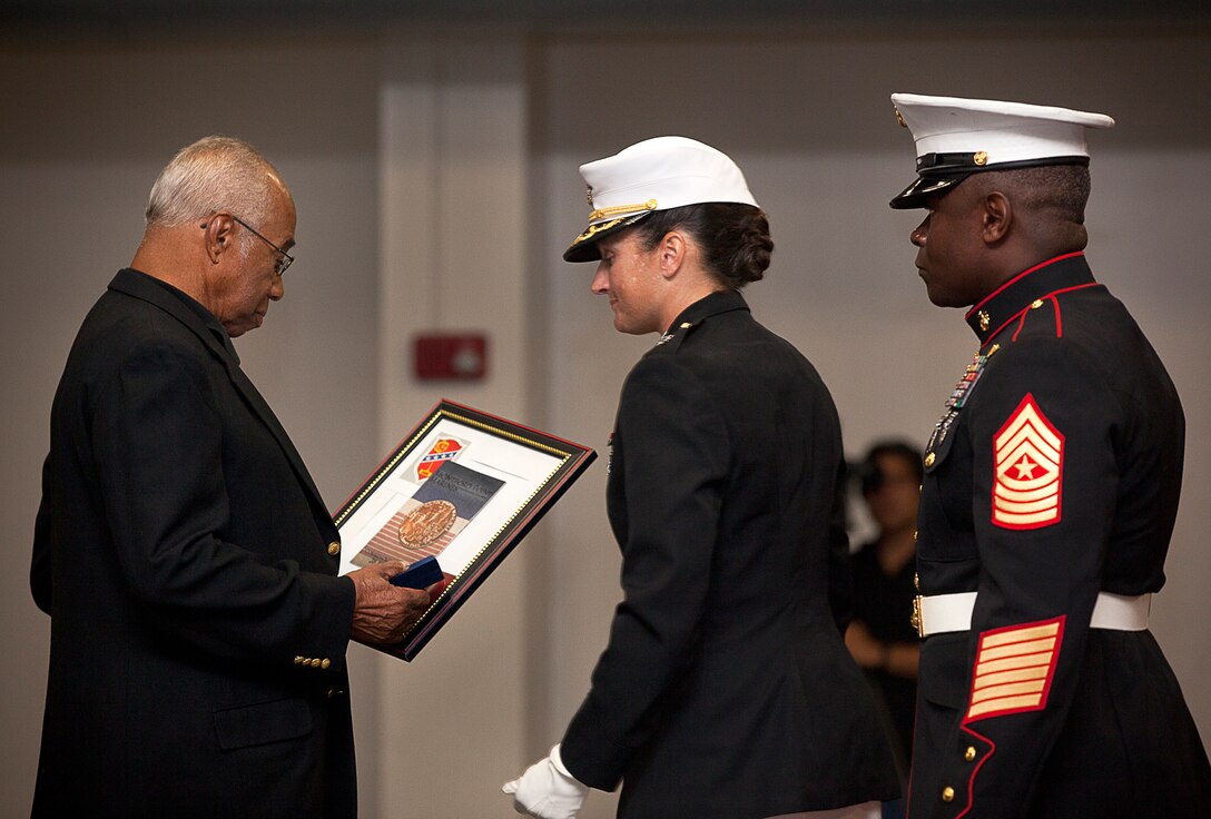 Former U.S. Marine Sgt. William S. Harris, Jr. (left), a World War II-era Montford Point Marine and Molokai, Hawaii, native, gazes at the Congressional Gold Medal he received from Lt. Col. Carolyn Bird (center), the commanding officer of Headquarters Battalion, during a ceremony held in his honor on Marine Corps Base Hawaii, Aug. 27, 2012. Harris served in the Marine Corps from 1943 to 1952. He is among approximately 20,000 African-American men who joined the Marine Corps between 1942 to 1949 and received segregated recruit training at Montford Point, N.C. More than 13,000 of these Marines served overseas during World War II. U.S. House and Senate leaders awarded the medal — the highest civilian honor awarded as the utmost expression of national appreciation for distinguished achievements and contributions — to the Montford Point Marines in a ceremony at the U.S. Capitol Visitors Center, June 27. The Commandant of the Marine Corps held a parade in their honor at Marine Barracks Washington the following day, during which they were presented replica bronze medals. Veterans who were unable to attend were honored during individual ceremonies across the U.S.