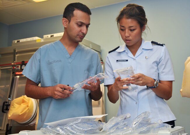 Ashfaq Shafiq, Veterans Affairs pharmacist, and Capt. Renee Shirakawa, 99th Medical Support Squadron pharmacist, check expiration dates and log numbers on intravenous bags before dispensing to patients Aug. 27, 2012, at Nellis Air Force Base, Nev. VA and 99th Medical Group personnel work together daily to provide care to veterans and Department of Defense beneficiaries.  (U.S. Air Force photo by Master Sgt. David Miller)