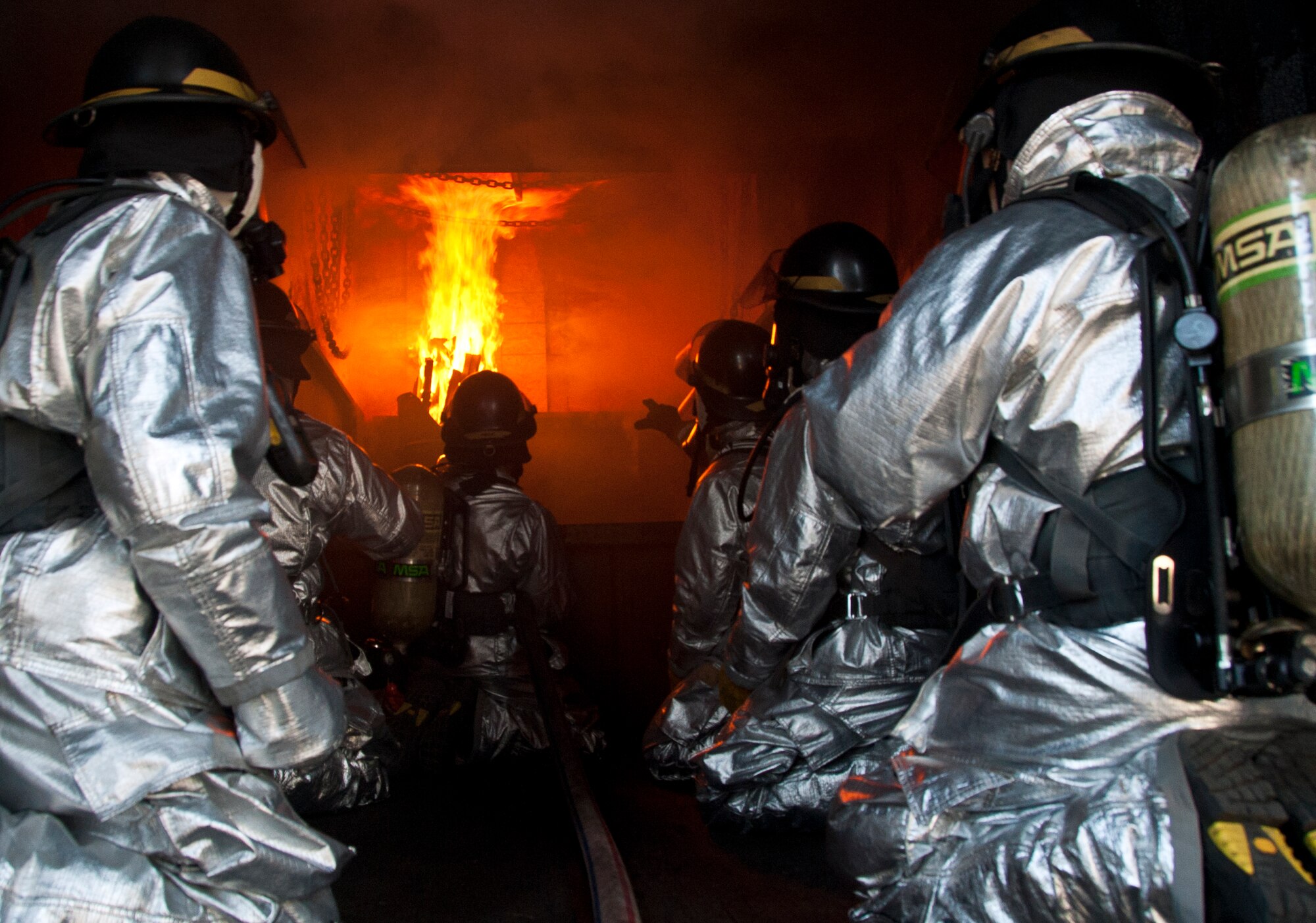 ALTUS AIR FORCE BASE, Okla. – Stacy Belk, Oklahoma State University fire service training instructor, shows members of the 97th Civil Engineer Squadron fire department where to spray water during a fire flashover exercise at the base training pit, Aug. 28, 2012. During the training, firefighters learned ways to suppress a fire flashover before it occurs, which gives them enough time to escape. (U.S. Air Force photo by Airman 1st Class Kenneth W. Norman / Released / 97th Air Mobility Wing Public Affairs)