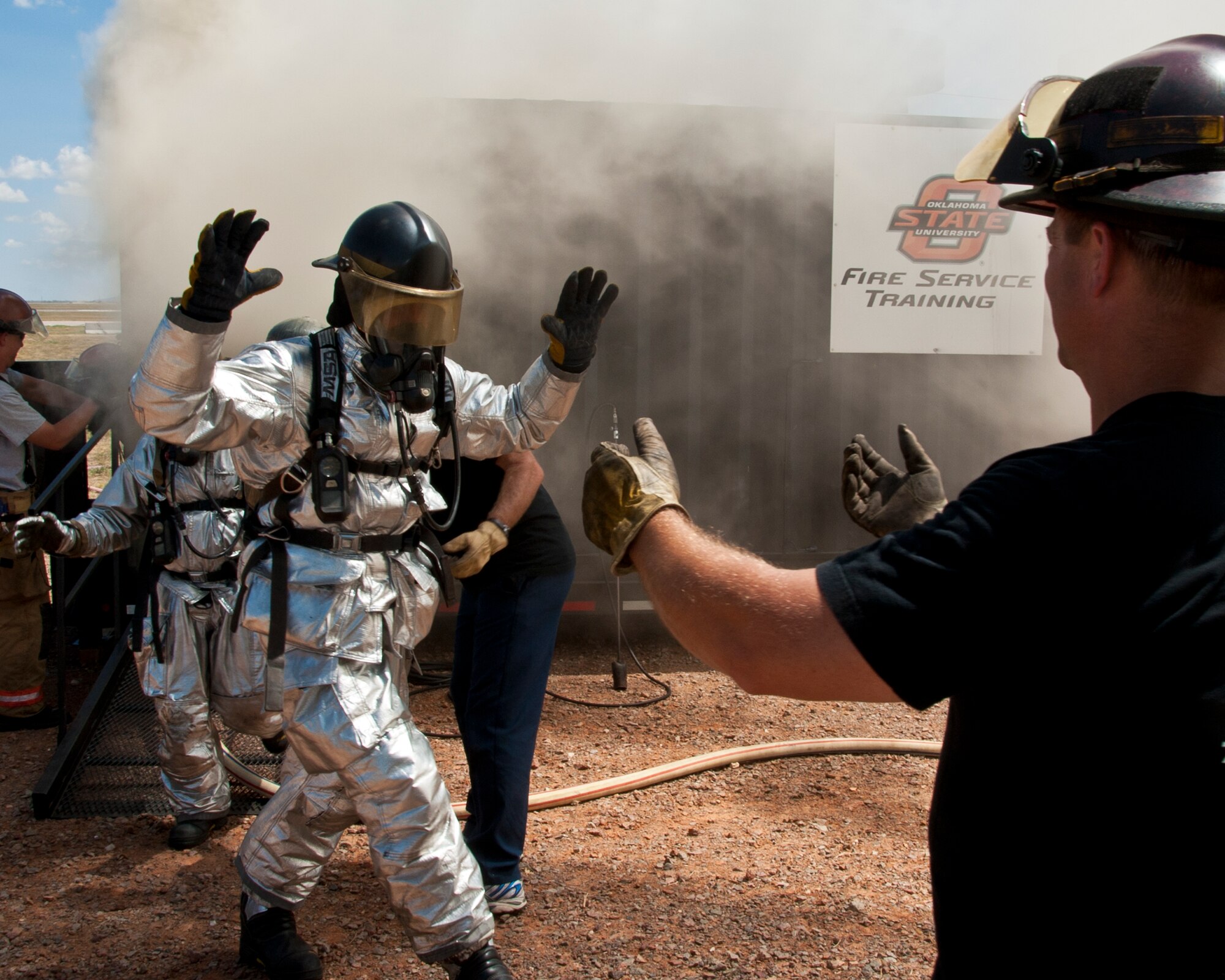 ALTUS AIR FORCE BASE, Okla. – Stacy Belk, Oklahoma State University fire service training instructor, directs members of the 97th Civil Engineer Squadron fire department as they exit a fire flashover simulator, Aug. 28, 2012 at the training pit. The flashover exercise teaches firefighters how to recognize when a flashover is going to occur and how to suppress it long enough to escape. (U.S. Air Force photo by Airman 1st Class Kenneth W. Norman / Released / 97th Air Mobility Wing Public Affairs)