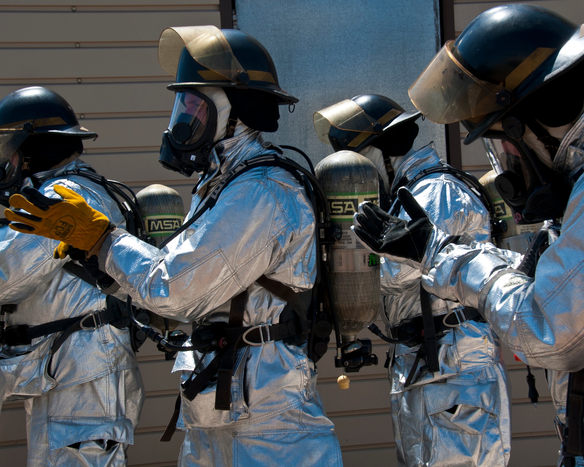 ALTUS AIR FORCE BASE, Okla. – Members of the 97th Civil Engineer Squadron fire department finish putting on their gear before entering a fire flashover simulator at the training pit, Aug. 28, 2012. The flashover exercise teaches firefighters how to recognize when a flashover is going to occur and how to suppress it long enough to escape. (U.S. Air Force photo by Airman 1st Class Kenneth W. Norman / Released / 97th Air Mobility Wing Public Affairs)
