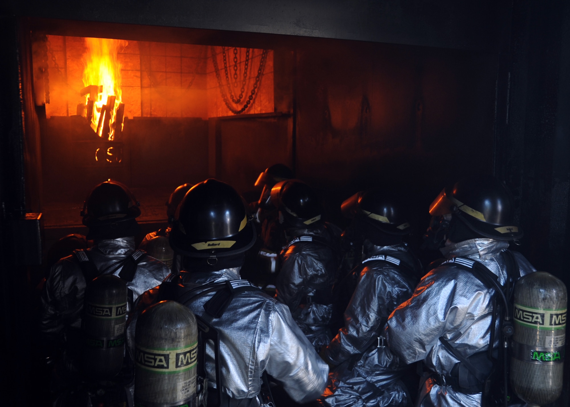 ALTUS Air Force Base, Okla. – Stacy Belk, Oklahoma State University fire service training instructor, shows members of the 97th Civil Engineer Squadron fire department, where to spray water during a fire flashover exercise at the base training pit, Aug. 28, 2012. A flashover occurs when heat from the flames are absorbed into the upper walls causing a room to burst into a high temperature explosion. (U.S. Air Force photo by Airman 1st Class Franklin R. Ramos / 97th Air Mobility Wing / Released)
