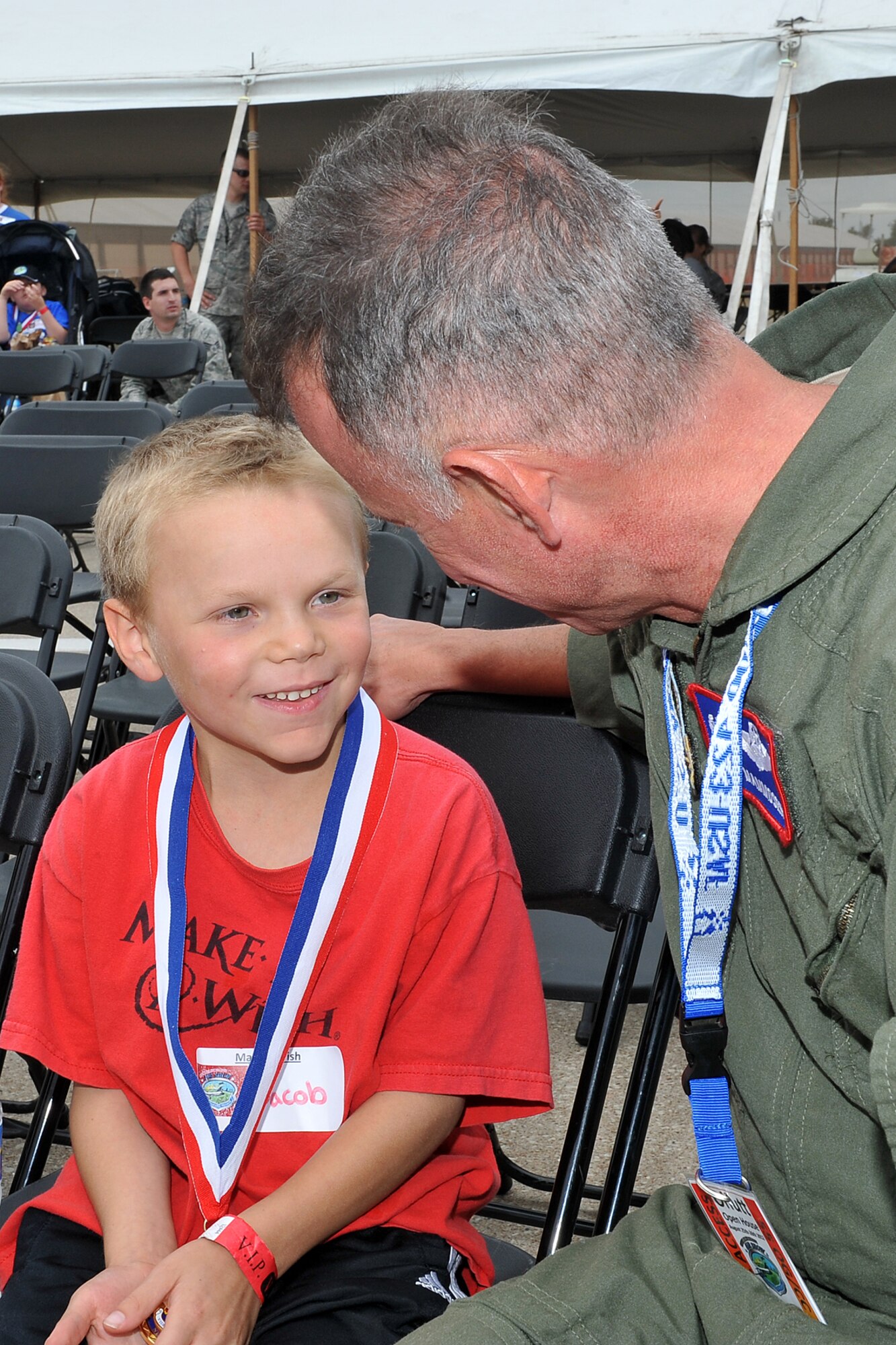 Jacob McClellan, son of Mike and Amanda McClellan, talks to U.S. Air Force Col. Russell Mammoser, 55th Operations Group commander, after he was presented a medallion during the 2012 Defenders of Freedom Special Needs Air Show on Offutt Air Force Base, Neb., Aug. 24. Jacob is one of 22 children who got to attend the event with their families. (U.S. Air Force photo by Charles Haymond/Released)