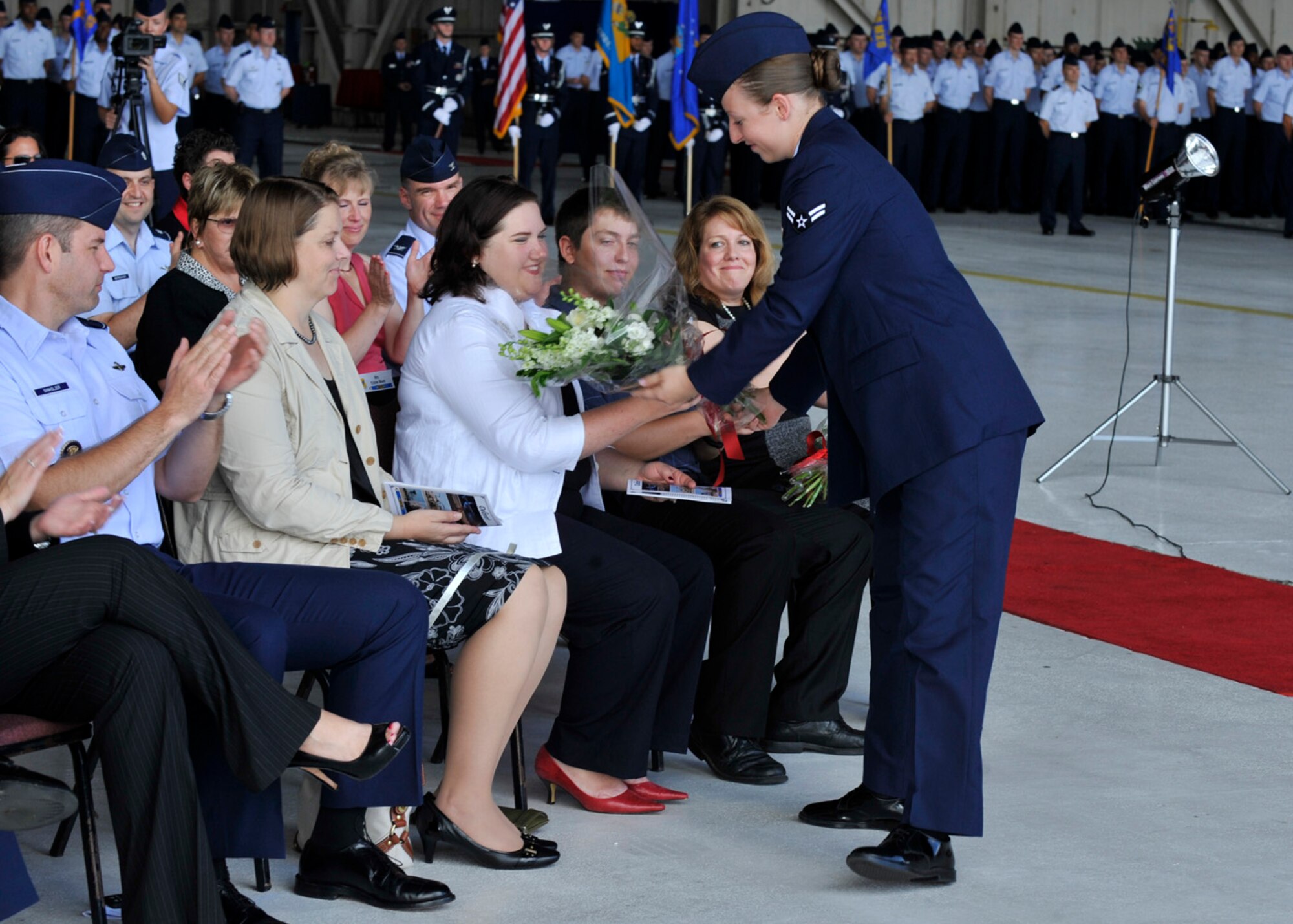 Kristin Moore, wife of the 436th Airlift Wing commander Col. Richard Moore, Jr., receives a bouquet of flowers from Airman 1st Class Caroline Caballero during the change of command ceremony Aug. 27, 2012, on Dover Air Force Base, Del. Moore assumed command from Col. Mark Camerer. (U.S. Air Force photo by Tech. Sgt. Chuck Walker)