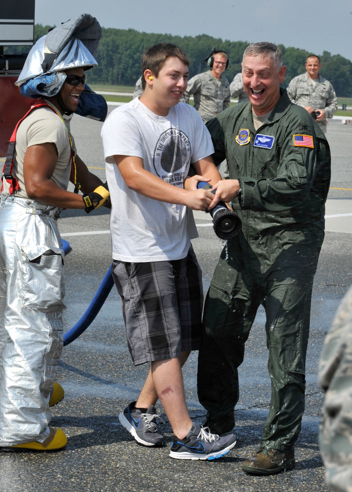 Col. Mark Camerer, commander of the 436th Airlift Wing, attempts to wrestle a fire hose away from his son, Mike, at the flightline following his Fini Flight Aug. 24, 2012, on Dover Air Force Base, Del. Camerer relinquished command of the 436th Airlift Wing in a change of command ceremony on Monday. (U.S. Air Force photo by Tech. Sgt. Chuck Walker)
