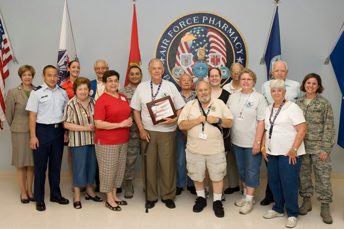 Katherine Miller, deputy executive director of the Nevada Office of Veterans Services, U.S. Air Force Col. Carol Yanarella, 99th Air Base Wing vice commander, stand with volunteers and members of the Satellite Pharmacy Aug. 23, 2012, at Nellis Air Force Base, Nev. With the help of Volunteers at the Satellite Pharmacy they are number one in the Air Combat Command. (U.S. Air Force photo by Airman 1st Class Daniel Hughes)