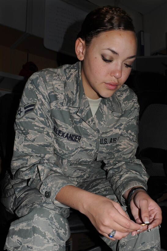 U.S. Air Force Airman 1st Class Mariah Alexander, 633rd Medical Support Squadron pharmacy technician, reflects on her first year in the Air Force at Langley Air Force Base, Va., Aug. 23, 2012. Alexander was presented with a coin that belonged to her stepfather, retired Chief Master Sgt. Eugene Burroughs Jr., who passed away three weeks before her Air Force Anniversary. (U.S. Air Force photo by Airman 1st Class Teresa Aber/Released)