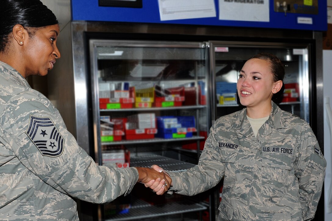U.S. Air Force Chief Master Sgt. Trae King, 633rd Air Base Wing Command Chief, presents a coin to Airman 1st Class Mariah Alexander, 633rd Medical Support Squadron pharmacy technician, at Langley Air Force Base, Va., Aug. 23, 2012. The coin belonged to Alexander’s stepfather, retired Chief Master Sgt. Eugene Burroughs Jr., who passed away three weeks before Alexander’s first Air Force anniversary. (U.S. Air Force photo by Airman 1st Class Teresa Aber/Released)