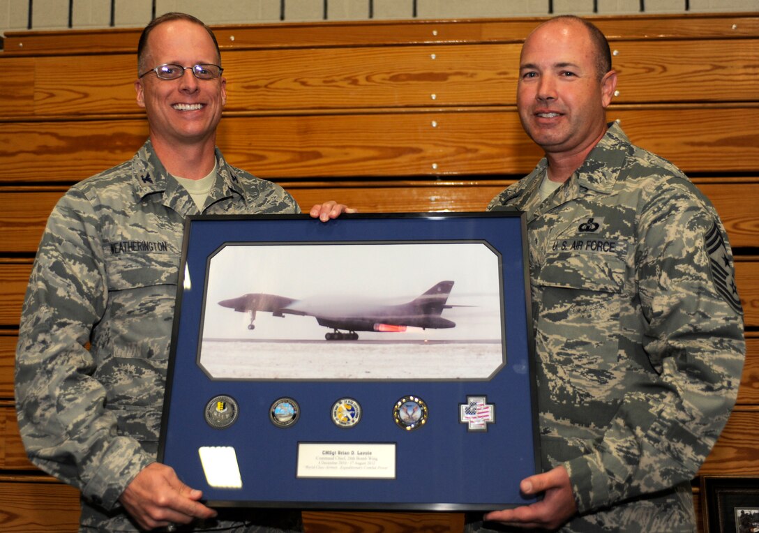 Col. Mark Weatherington, 28th Bomb Wing commander, presents Chief Master Sgt. Brian Lavoie, former 28th BW command chief, with a framed photo of a B-1 during a going-away event at the Bellamy Fitness Center on Ellsworth Air Force Base, S.D., Aug. 17, 2012. Weatherington, along with several others, thanked Lavoie for his service and dedication to the wing during his time at Ellsworth and wished him luck at his next assignment as the 72nd Air Base Wing command chief at Tinker AFB, Okla. (U.S. Air Force photo by Airman Ashley J. Woolridge/Released)