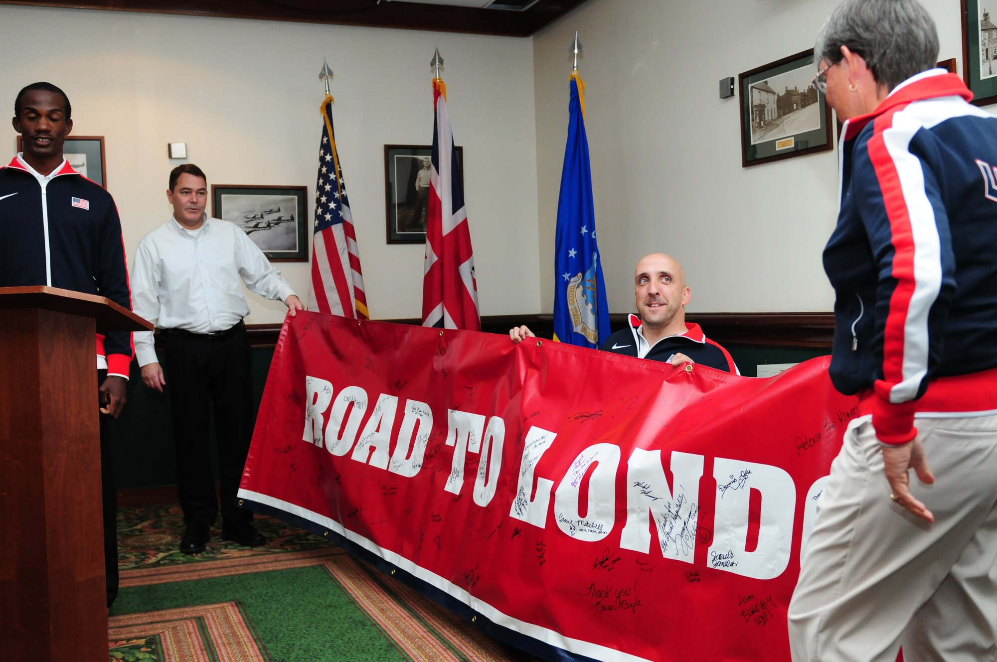 ROYAL AIR FORCE LAKENHEATH, England -- Members of the U.S. Paralympic Track & Field team present the Liberty Wing with a banner during the send-off dinner at Eagle's Landing Aug. 23, 2012. More than 50 U.S. Paralympians and hopefuls honed their skills and made final preparations here Aug. 18 through 25 for competition in the London 2012 Paralympic Games. (U.S. Air Force photo by Senior Airman Lausanne Morgan)