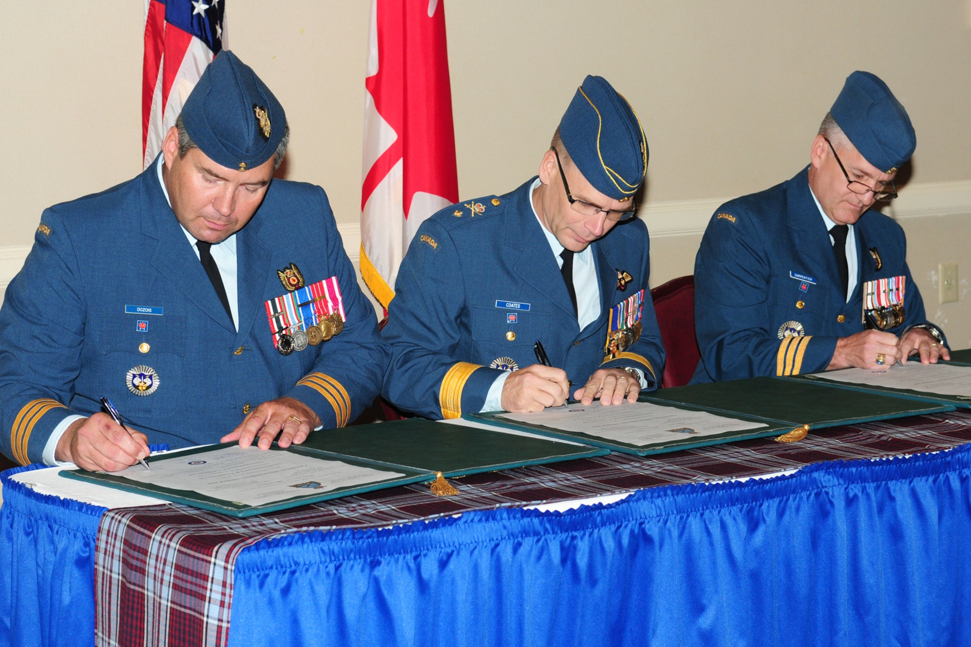 Lt. Col. Peter Dozois, left, Brig. Gen. Christopher Coates and Lt. Col. Patrick Carpentier sign documents signifying a change of command for the Canadian Detachment at Tinker Air Force Base on Aug. 15 at the Tinker Club. Colonel Carpentier relinquished command of the detachment to Colonel Dozois, while General Coates served as the presiding officer. (Air Force photo by Kelly White)