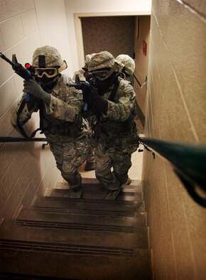 A fire team of 72nd Security Forces Squadron Airmen up a stairwell in pursuit of an active shooter, during a recent training exercise. Airmen used real weapons firing “sim” rounds, black-powder propelled markers, which sting “a little more than a paintball” participants said. The ammunition provides an extra level of realism.  (Air Force photo by Micah Garbarino)