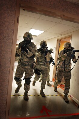 A fire team of 72nd Security Forces Squadron Airmen move from room to room, in pursuit of an active shooter, during a recent training exercise. Airmen used real weapons firing “sim” rounds, black-powder propelled markers, which sting “a little more than a paintball” participants said. The ammunition provides an extra level of realism.  (Air Force photo by Micah Garbarino)