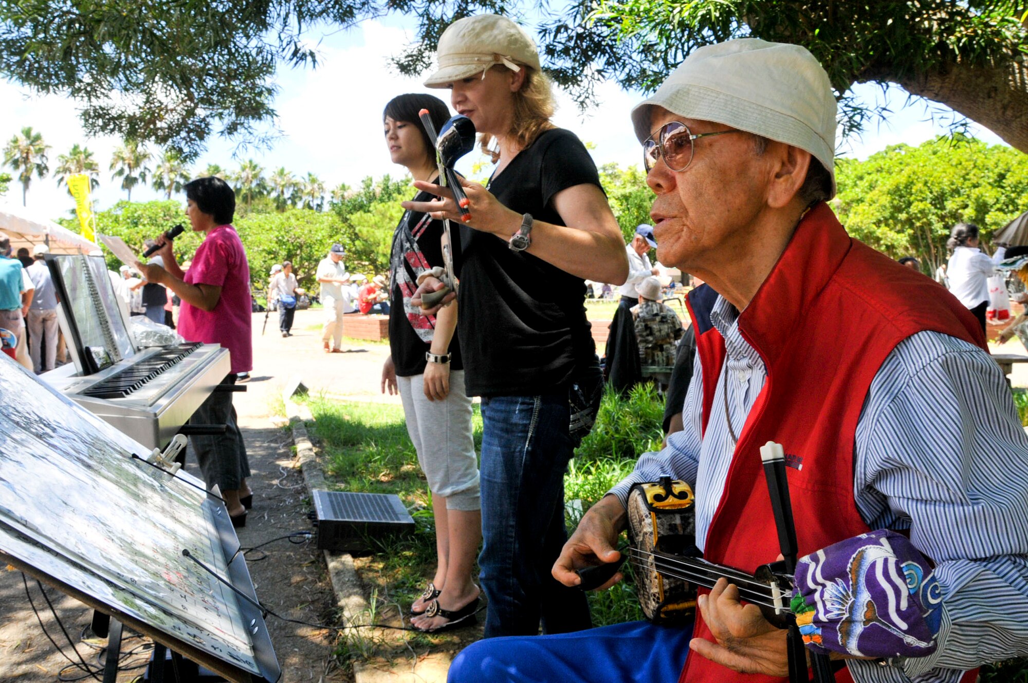 Local volunteers performed for the less fortunate while waiting to get their food during a volunteer event to feed the homeless in Yogi Park in Naha Aug. 18, 2012. Before eating, the local volunteers sang and danced for the less fortunate people. (U.S. Air Force photo/Staff Sgt. Darnell T. Cannady)