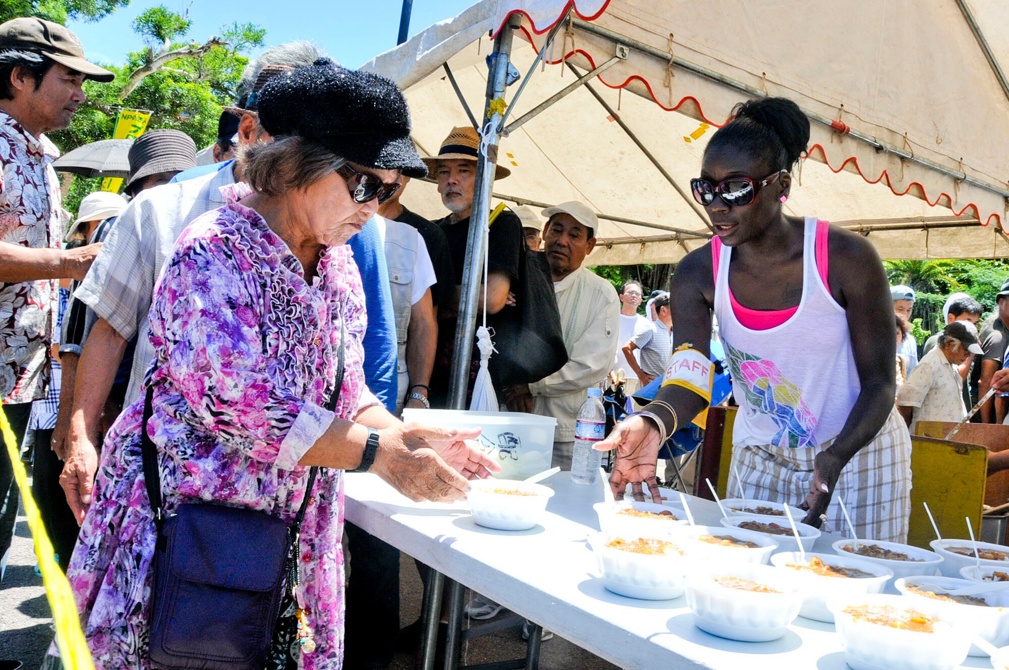 U.S Air Force Tech. Sgt. Yennetta Taylor, Kadena 5/6 Club member, hands out bowls of curry during a volunteer event to feed the homeless in Yogi Park in Naha on Aug. 18, 2012. Nine members from the 5/6 Club volunteered their Saturday to serve food to the less fortunate. Meals included curry, rice, sandwiches, and drinks. (U.S. Air Force photo/Staff Sgt. Darnell T. Cannady)