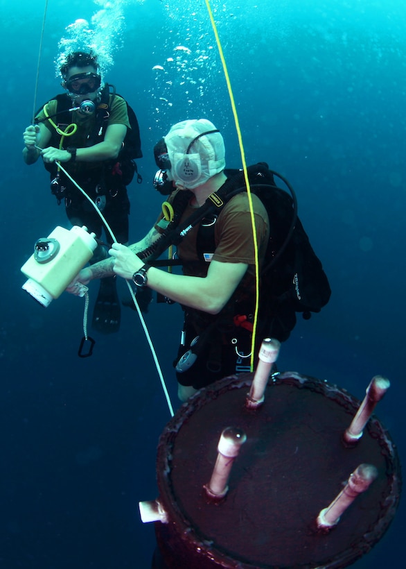 U.S. and Singapore navy divers examine a simulated underwater mine as part of a mine-counter measure scenario during Tricrab 2012 in Guam, Aug. 27, 2012.