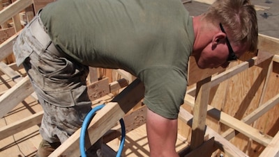 Cpl. Matthew R. Flynn, an assistant squad leader with Engineer Detachment, Combat Logistics Battalion 11, 11th Marine Expeditionary Unit, uses a nail gun to secure part of the structure of a Southwest Asia hut during a field operation at Camp Pendleton, Calif., June 20. Constructing the hut readied them for any humanitarian assistance or disaster relief missions where infrastructure damage has occurred.