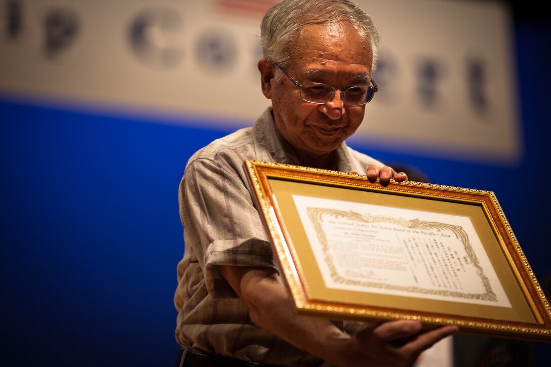 FUSSA CITY, Japan -- Mr. Hisato Nozawa, Fussa-Yokota Goodwill Exchange Club president, receives a certificate of appreciation at the Fussa-Yokota Friendship Concert, Fussa City, Japan on Aug. 28, 2012. Nozawa was publically thanked by the Band of the Pacific-Asia for his role as sponsor for the concert. (U.S. Air Force photo by Josh Voyles))