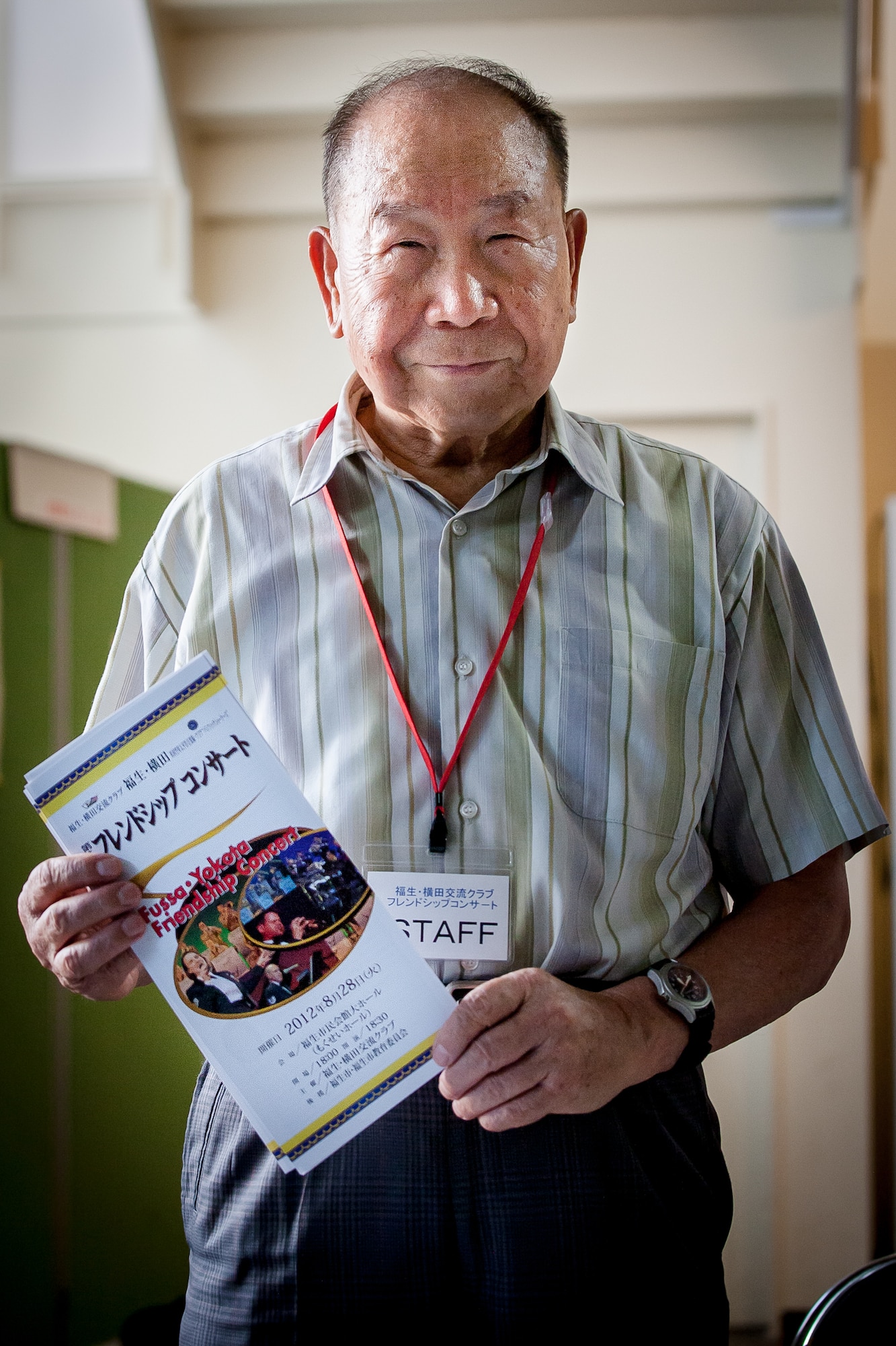FUSSA CITY, Japan -- Retired Japan Air Self-Defense Force Maj. Gen. Takeshi Ishikawa, Fussa-Yokota Goodwill Exchange Club advisor, poses for a photo at the Fussa-Yokota Friendship Concert, Fussa City, Japan on Aug. 28, 2012. Ishikawa handed out concert programs as people entered the hall and began to line up for the show. (U.S. Air Force photo by Staff Sgt. Josh Voyles)