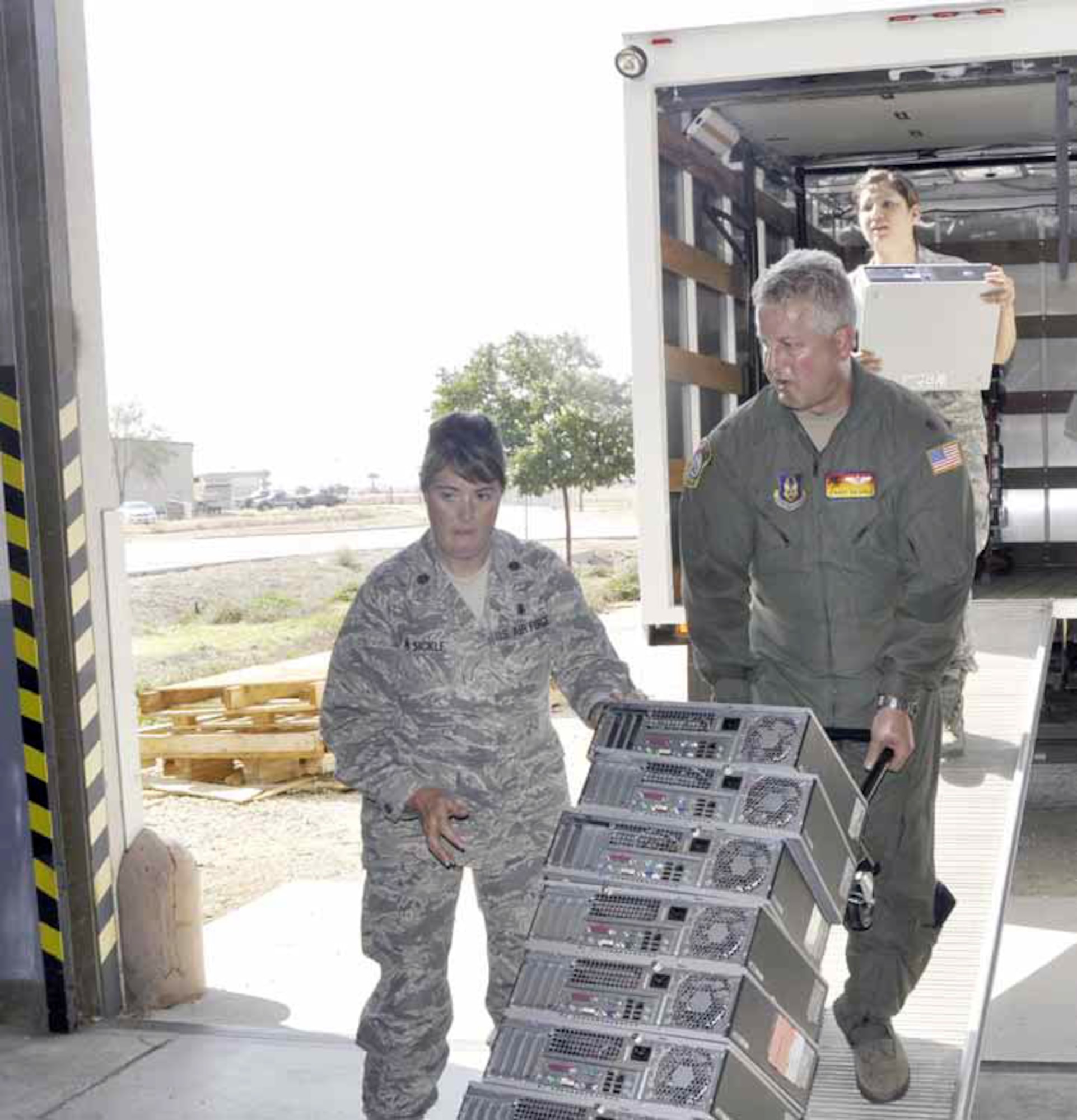 Maj. Michelle Van Sickle, executive officer, 452nd Air Mobility Wing, guides Maj. Barry Van Sickle, flight nurse, 452nd Aeromedical Evacuation Squadron, down a loading ramp during the Tech Refresh computer turn-in, Aug. 23. Senior Airman Isis Ponce, administrator, 452 AMW public affairs, pictured at top of the ramp, along with Capt. James Studer (not pictured), rallied to collect more than 100 computers for exchange. The Tech Refresh program is set-up to replace expired computers with up-to-date systems on a one-for-one swap. (U.S. Air Force photo by Darnell Gardner)