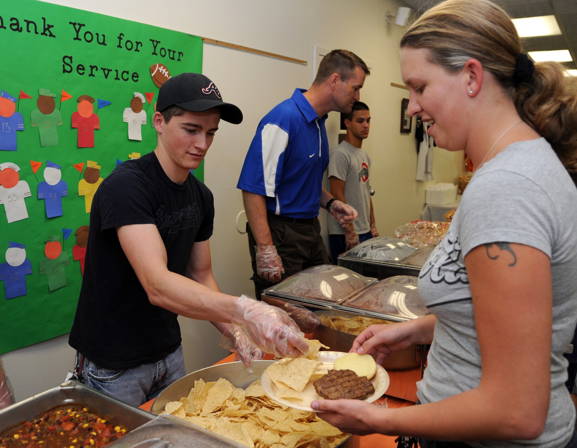 Airman 1st Class Cody O’Connell, left, an air traffic controller with the 71st Operations Support Squadron, serves some chips to Airman 1st Class Lydia Lewis, a dental technician with the 71st Medical Operations Squadron, during the Singles’ International Gourmet Meal Opportunity Aug. 27 in the Community Chapel Activity Center at Vance Air Force Base, Okla. (U.S. Air Force photo/ Airman 1st Class Frank Casciotta)