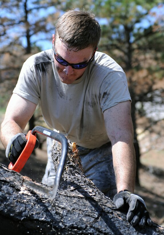 Cadet 2nd Class Warren McGriff, of Cadet Squadron 05, cuts through a tree during fire mitigation and cleanup efforts in the Mountain Shadows neighborhood Sunday. Mountain Shadows was one of the hardest hit areas during the recent Waldo Canyon Fire that destroyed 346 homes.  (U.S. Air Force Photo/Tech. Sgt. Raymond Hoy)