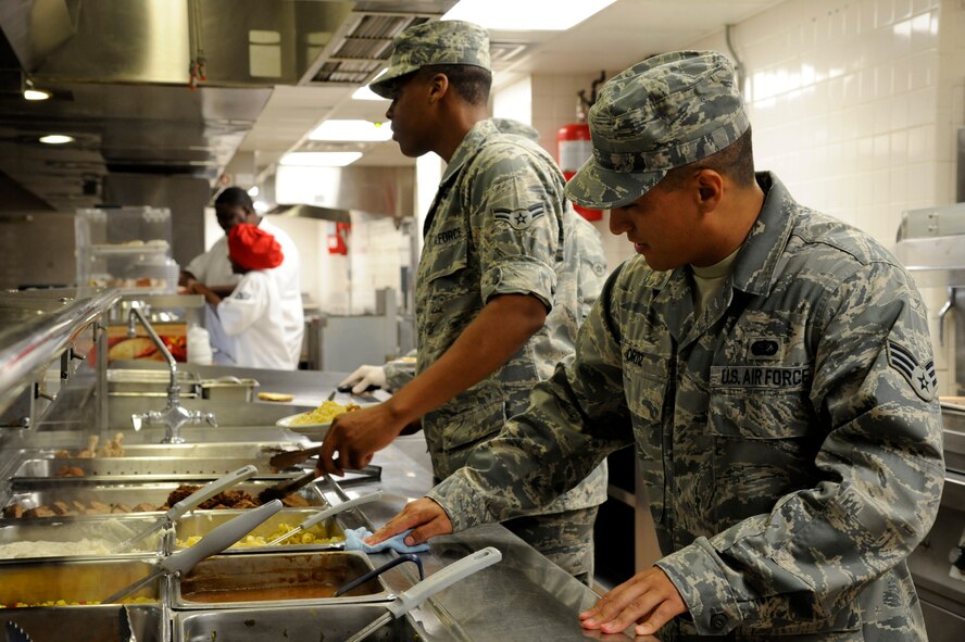 Senior Airman Jose Ortiz, 2nd Force Support Squadron, cleans the serving line as Airman 1st Class Yontaireus McCray, 2 FSS, serves food on Barksdale Air Force Base, La., Aug 28. Food service Airmen at the Red River Dining Facility are responsible for the preparation and serving of meals and keeping the facility clean. (U.S. Air Force photo/Airman 1st Class Andrew Moua)(RELEASED)
