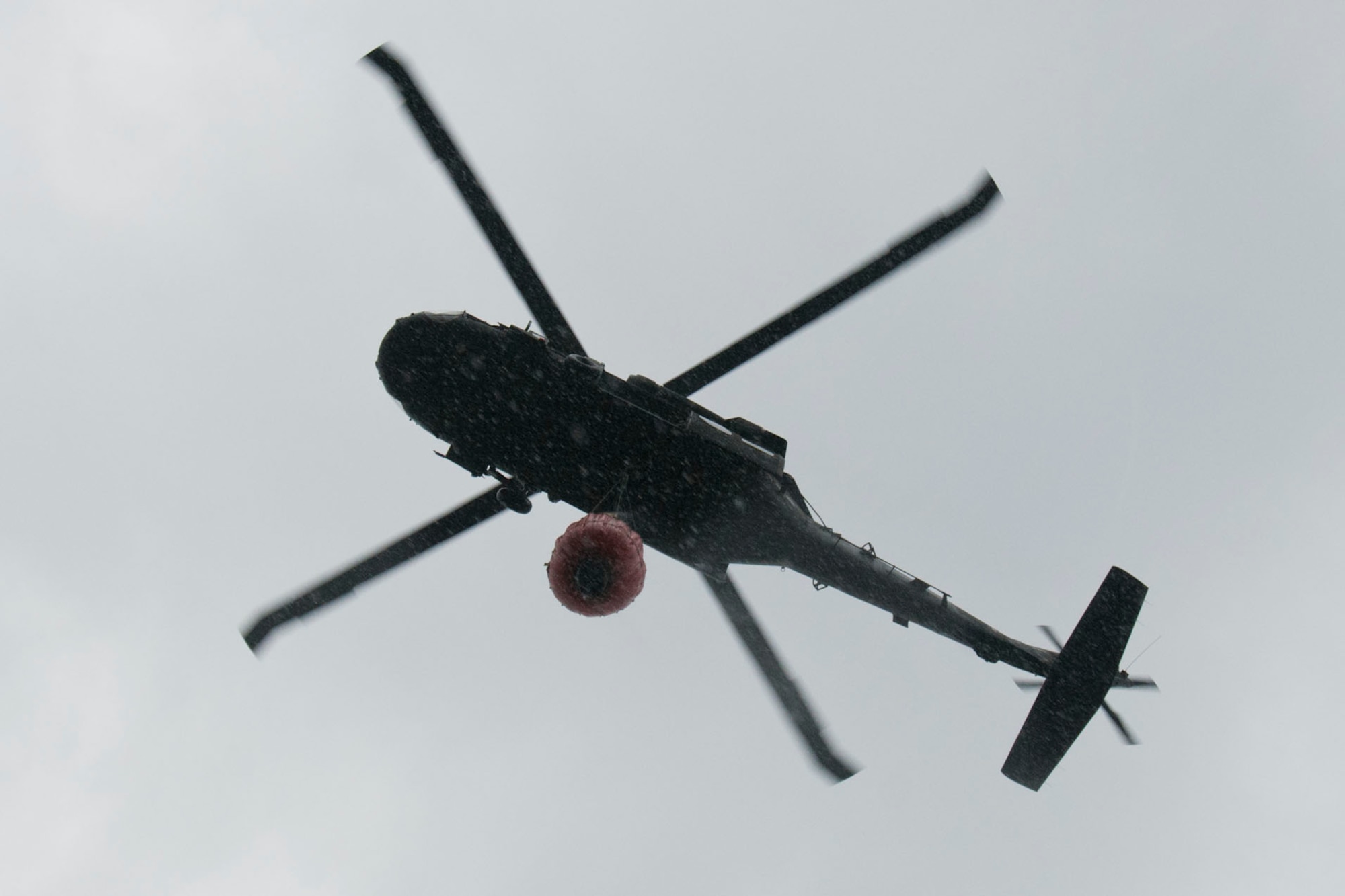 A Massachusetts Army National Guard UH-60 Blackhawk helicopter, from the Army Aviation Support Facility #1 on the Massachusetts Military Reservation, hovers over Snake Pond in Sandwich, Mass., after it fills a "Bambi Bucket" with water during a demonstration of the firefighting system for Paraguayan air force pilots, Aug. 28, 2012. Five Paraguayan air force pilots were in Massachusetts as part of the National Guard State Partnership Program, a 20-year-old program that partners states with countries around the world to facilitate cooperation across all aspects of civilian-military affairs and encourage people-to-people ties at the state level. (Air National Guard photo by Master Sgt. Aaron Smith/Released)