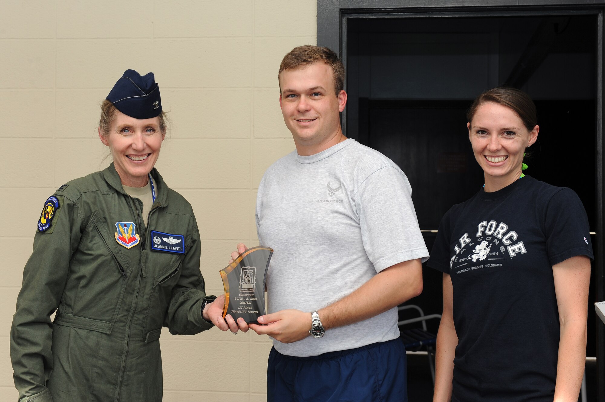 U.S. Air Force Col. Jeannie Leavitt, 4th Fighter Wing commander, presents the first place trophy to 2nd Lt. Richard Fox, 4th Communications Squadron officer in-charge, and 1st Lt. Heather Flynn, 4th CS operations flight commander, after a build-a-boat contest on Seymour Johnson Air Force Base, N.C., Aug. 22, 2012. After racing their boat across the Olympic pool with a fastest time of 42 seconds, the 4th CS received a trophy and a $150 Force Support Squadron gift card. (U.S. Air Force photo/Airman 1st Class John Nieves Camacho/Released)