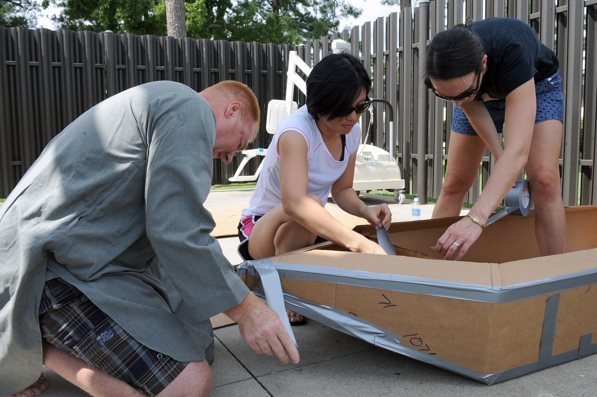 Participants in a build-a-boat competition tape parts of a cardboard boat on Seymour Johnson Air Force Base, N.C., Aug. 22, 2012. Teams were given tape and strict guidelines for construction when building the vessel. (U.S. Air Force photo/Airman 1st Class John Nieves Camacho/Released)