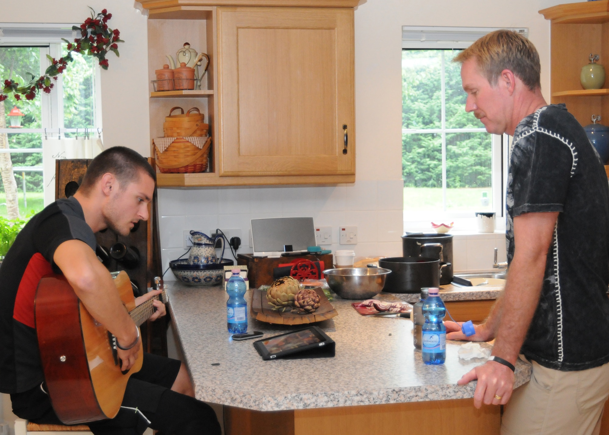 RAF MILDENHALL, England - Jaryyd Wallace, left, U.S. Paralympic Team track and field member, tries to work out the chords to a song as Chief Master Sgt. Christopher Powell, 100th Air Refueling Wing command chief, listens Aug. 23, 2012, in the Powell residence. The Powell family was sponsoring Wallace while he was in the local area prior to participating in the London 2012 Paralympic games. (U.S. Air Force photo/Tech. Sgt. Neal X. Joiner)
