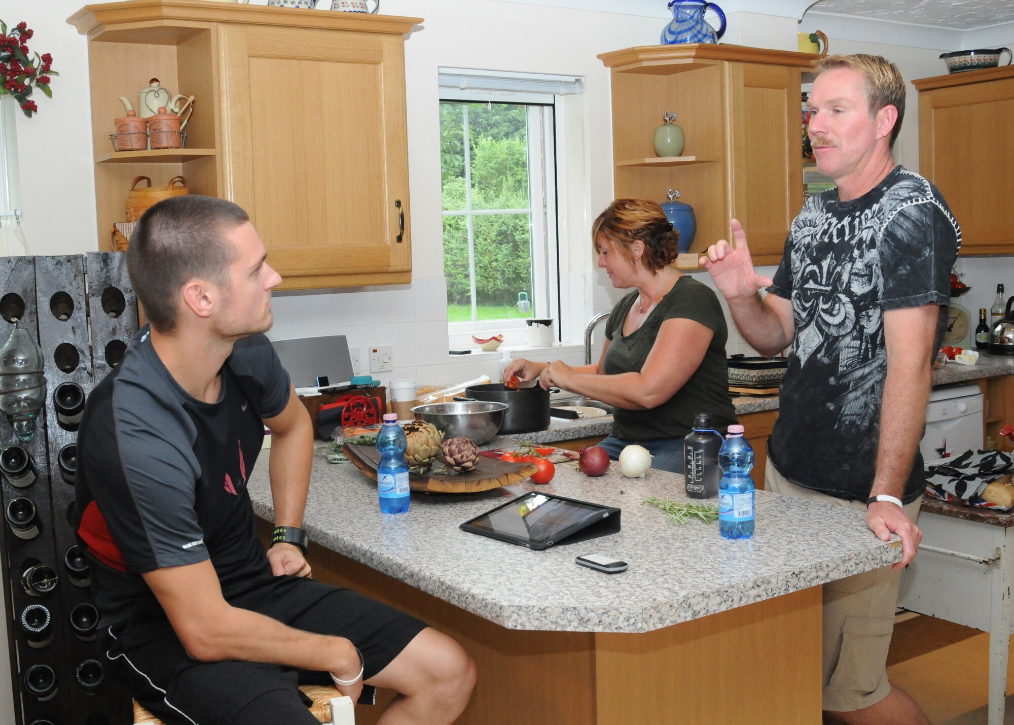RAF MILDENHALL, England - Jaryyd Wallace, left, U.S. Paralympic Team track and field member, and Chief Master Sgt. Christopher Powell, 100th Air Refueling Wing command chief, chat as Sharon Powell prepares dinner Aug. 23, 2012, in the Powell residence. The Powell family was sponsoring Wallace while he was in the local area prior to participating in the London 2012 Paralympic games. (U.S. Air Force photo/Tech. Sgt. Neal X. Joiner)