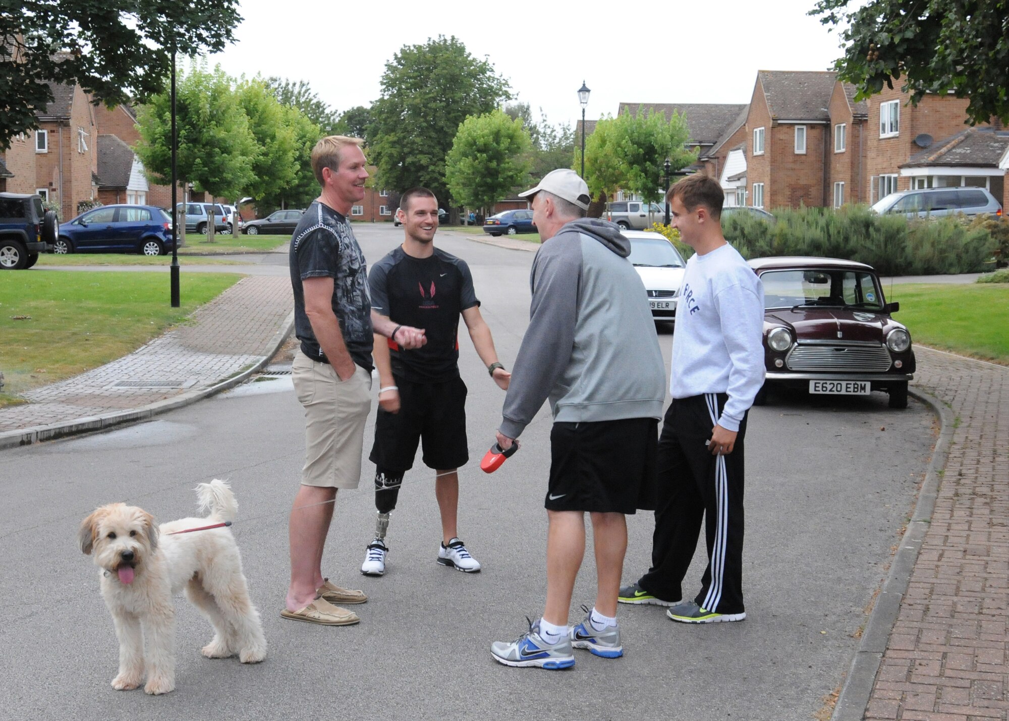 RAF MILDENHALL, England - From left, Chief Master Sgt. Christopher Powell, 100th Air Refueling Wing command chief, and Jaryyd Wallace, U.S. Paralympic Team track and field member, speak with Jim Thompson and his son, Dillon, outside the Powell residence Aug. 23, 2012. The Powell family was sponsoring Wallace while he was in the local area prior to participating in the London 2012 Paralympic games. (U.S. Air Force photo/Tech. Sgt. Neal X. Joiner)