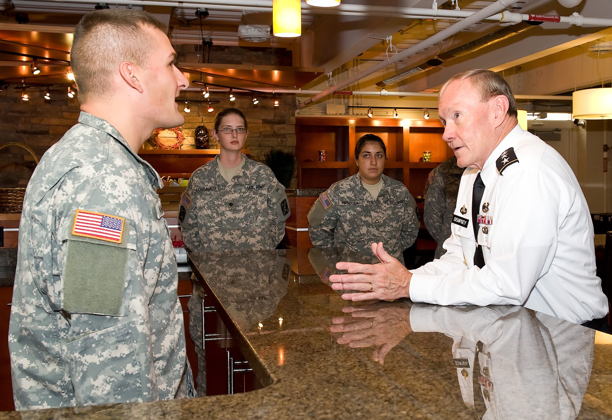Army Spc. Allen Amschler talks with the 18th Chairman of the Joint Chiefs of Staff, Army Gen. Martin E. Dempsey, Aug. 10, 2012 in the USO Lounge at the Charles C. Carson Center for Mortuary Affairs, as Spc. Ashley Coronado and Pfc. Ceara Hancock listen. Amschler, Coronado and Hancock are mortuary specialists from Fort Lee, Va., on assignment with the Armed Forces Medical Examiner System. (U.S. Air Force photo/Roland Balik)
