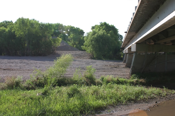 Emergency work by the NMDOT removed 3-5 feet of sediment and debris to increase channel capacity under the Highway 180 Bridge over the Gila River. The sediment is seen piled in the background.  The bridge is approximately 40 miles downstream from the Whitewater-Baldy Fire’s burn area.
