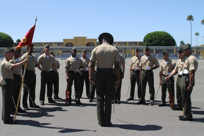 Staff Sgt. James Foster, squad instructor, Drill Instructor School, MCRD San Diego, demonstrates sword manual to DI School students on the parade deck aboard Marine Corps Recruit Depot, San Diego. Foster and other seasoned drill instructors serve as mentors for Marines who come to MCRD San Diego to become drill instructors.