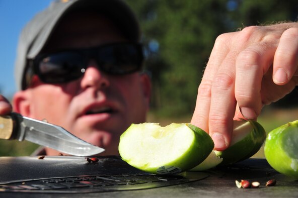 Steven Selser, 92nd Civil Engineer Squadron natural and cultural resources manager, slices green apples before he tosses them into the woods for deer as tasty treats Aug. 23, 2012 at Fairchild’s nature trail located near the Survival Evasion Resistance and Escape side of at Fairchild Air Force Base. Selser said initially deer wasn’t eating the apples, but after a few days he saw the slices completely gone. Since then, he has been tossing apples on the nature trail daily. (U.S. Air Force photo by Airman 1st Class Earlandez Young)
