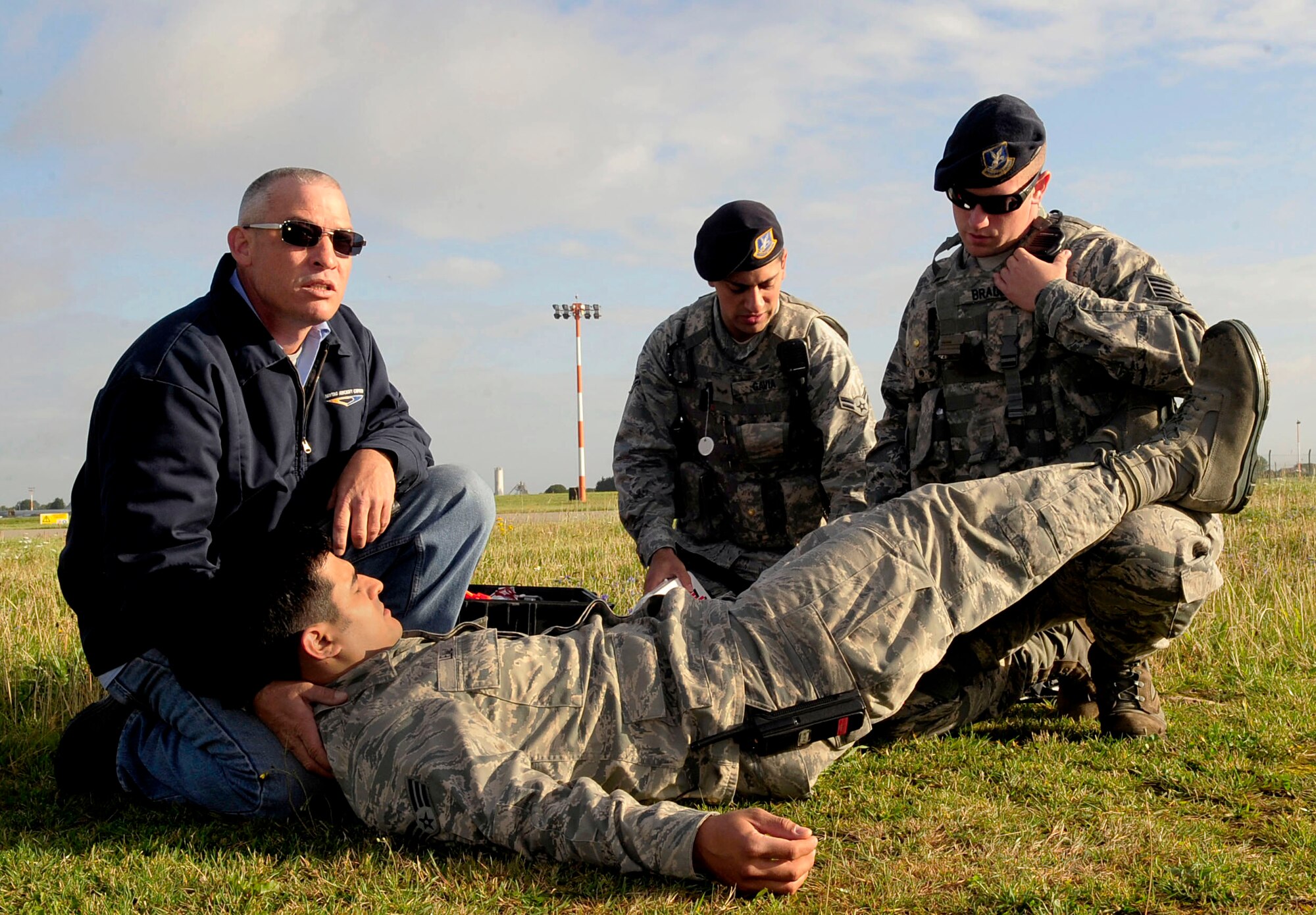 RAF MILDENHALL, England – Robert Hickerson, (left) a local contractor, along with Airman 1st Class Gregory Gavia, 100th Security Forces Squadron patrolman, and Staff Sgt. Jerry Bradley, 100th SFS patrolman, perform self-aid buddy care for Senior Airman Andrew Leal, 100th Logistics Readiness Squadron fuels technician, after a simulated fuel spill during a major accident response exercise Aug. 30, 2012, at RAF Mildenhall. Hickerson, Gavia and Bradley provide simulated treatment for shock to Leal until first responders could reach the scene and provide further medical treatment. (U.S. Air Force photo/Senior Airman Ethan Morgan)