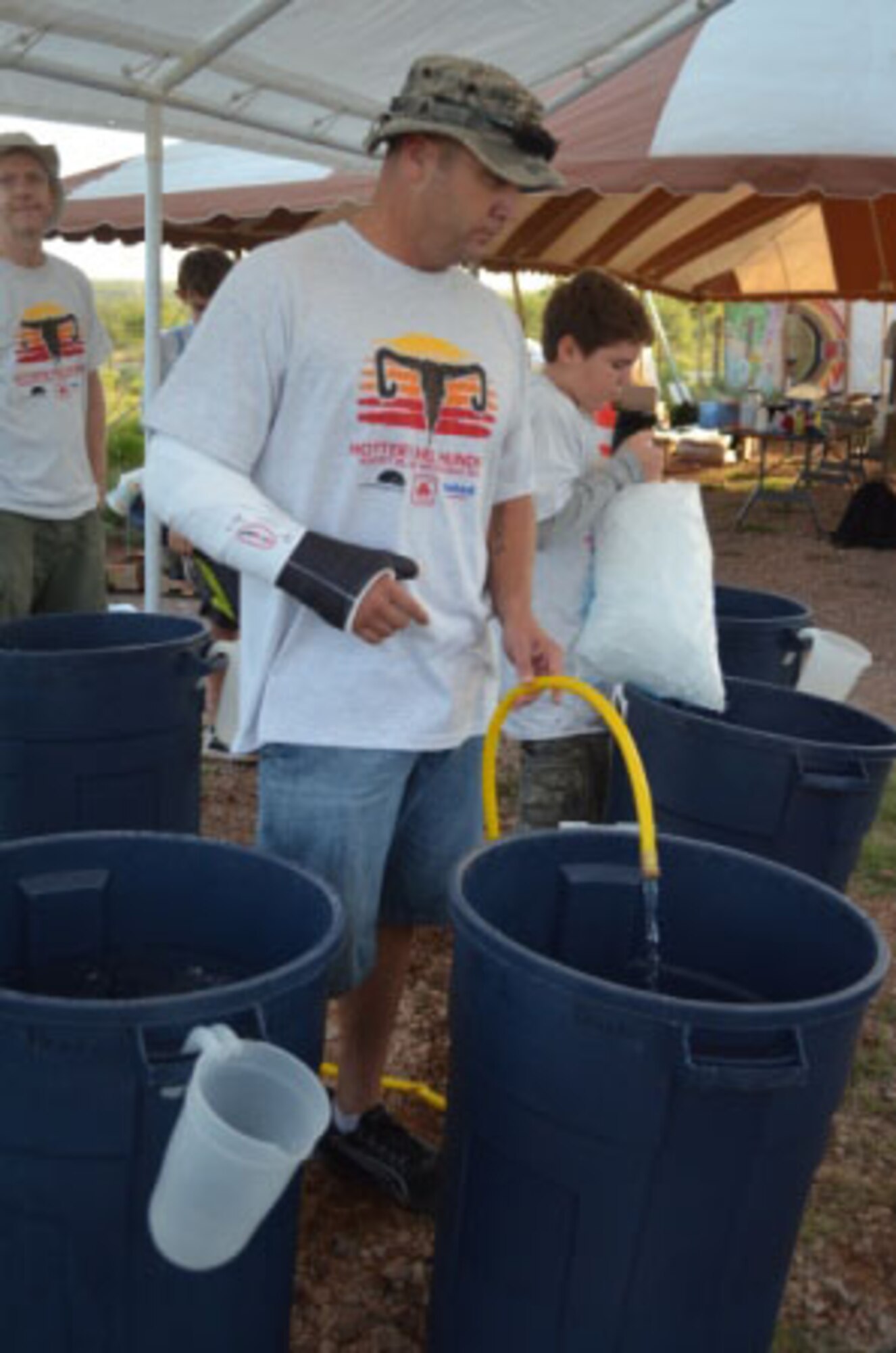Senior Master Sgt. Christopher Barks (left), 363rd Training Squadron, and Jacob Wang, Boy Scout Troop 13, empty ice as they prepare sports drinks for cyclists during the 31st annual Hotter N' Hell bike race Aug. 25, 2012.  The 363rd TRS pit stop was visited by 3,000-plus riders during the event. (U.S. Air Force courtesy photo)