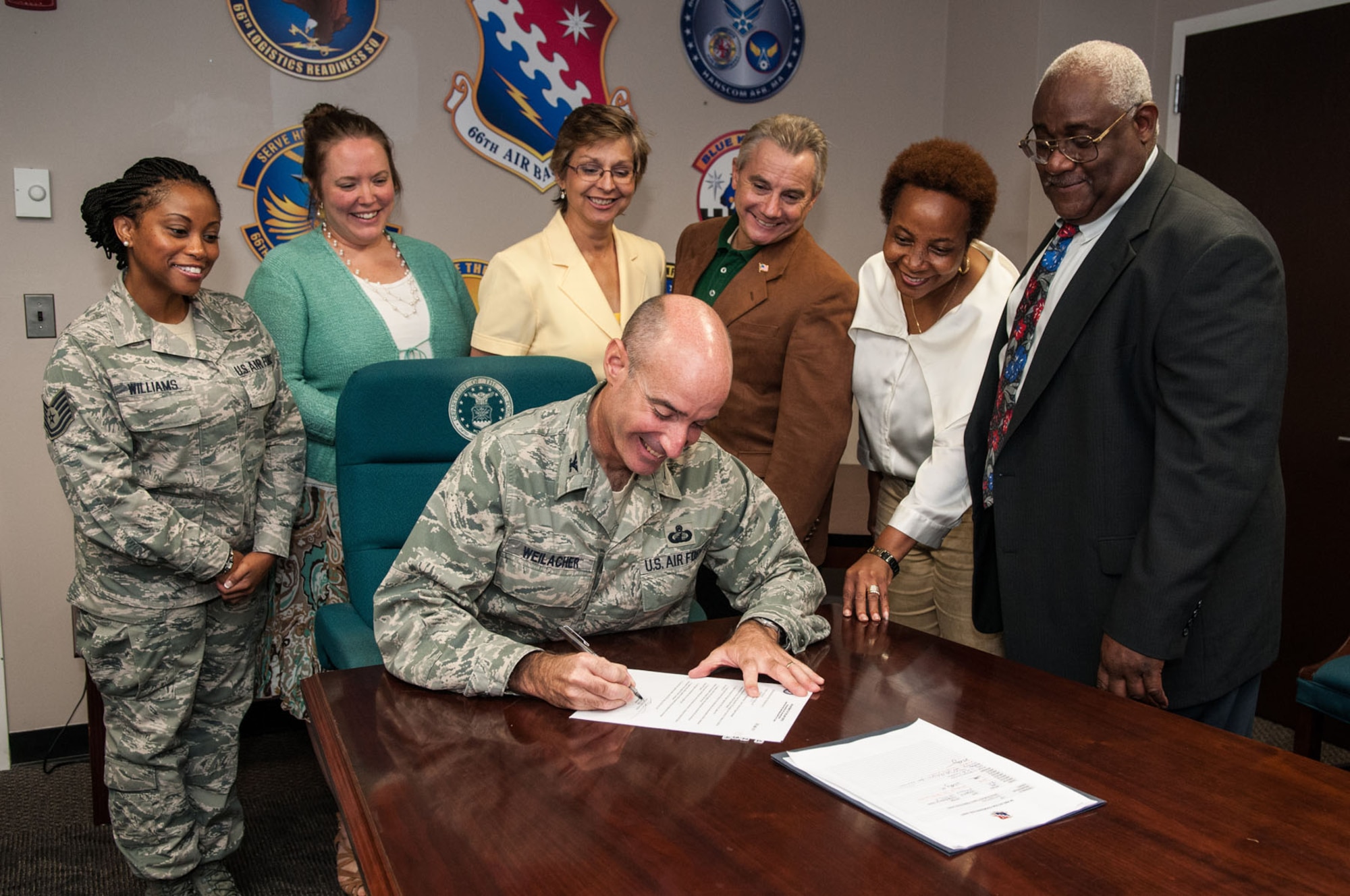HANSCOM AIR FORCE BASE, Mass. – Col. Lester A. Weilacher (seated), 66th Air Base Group commander, signs a Special Emphasis Program document in the commander’s conference room Aug. 28 as members of the Equal Opportunity office and SEP managers gather around. The Equal Opportunity office recently reignited SEP to implement creative approaches to recruitment, employment, placement and training in groups who are less represented based on the Civil Rights Act of 1964. (U.S. Air Force photo Rick Berry)