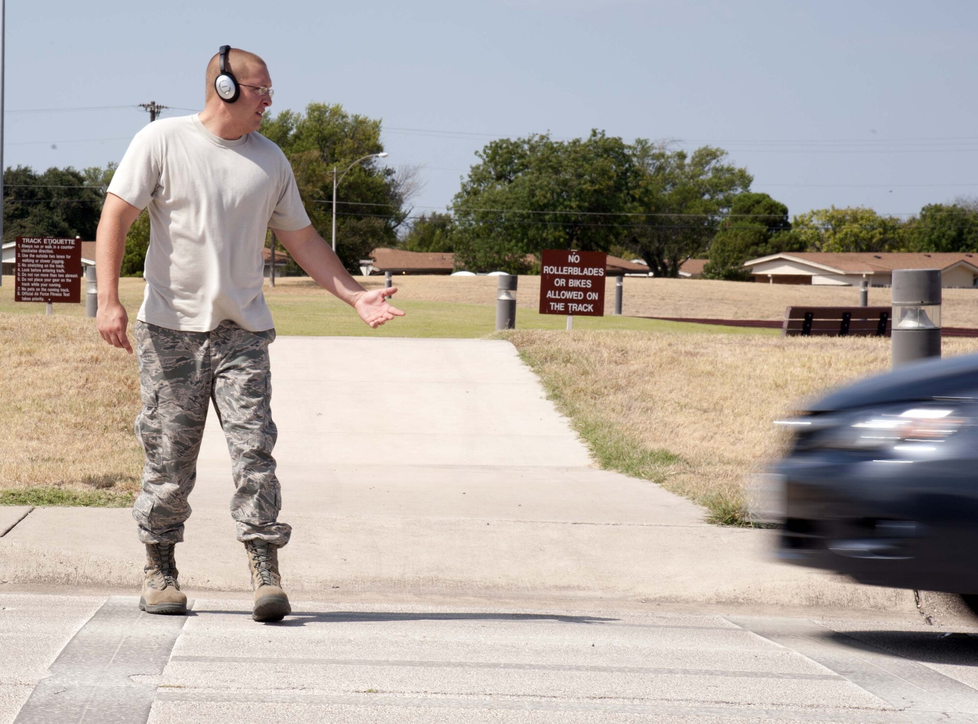 An Airman, out of regulations, crosses paths with a speeding vehicle after entering a crosswalk without removing his headphones at Laughlin Air Force Base, Texas, Aug. 22 2012. The Air Force Safety Center has written rules prohibiting the use of listening and entertainment devices when on a roadway. (U.S. Air Force photo illustration/Airman 1st Class Nathan Maysonet) 