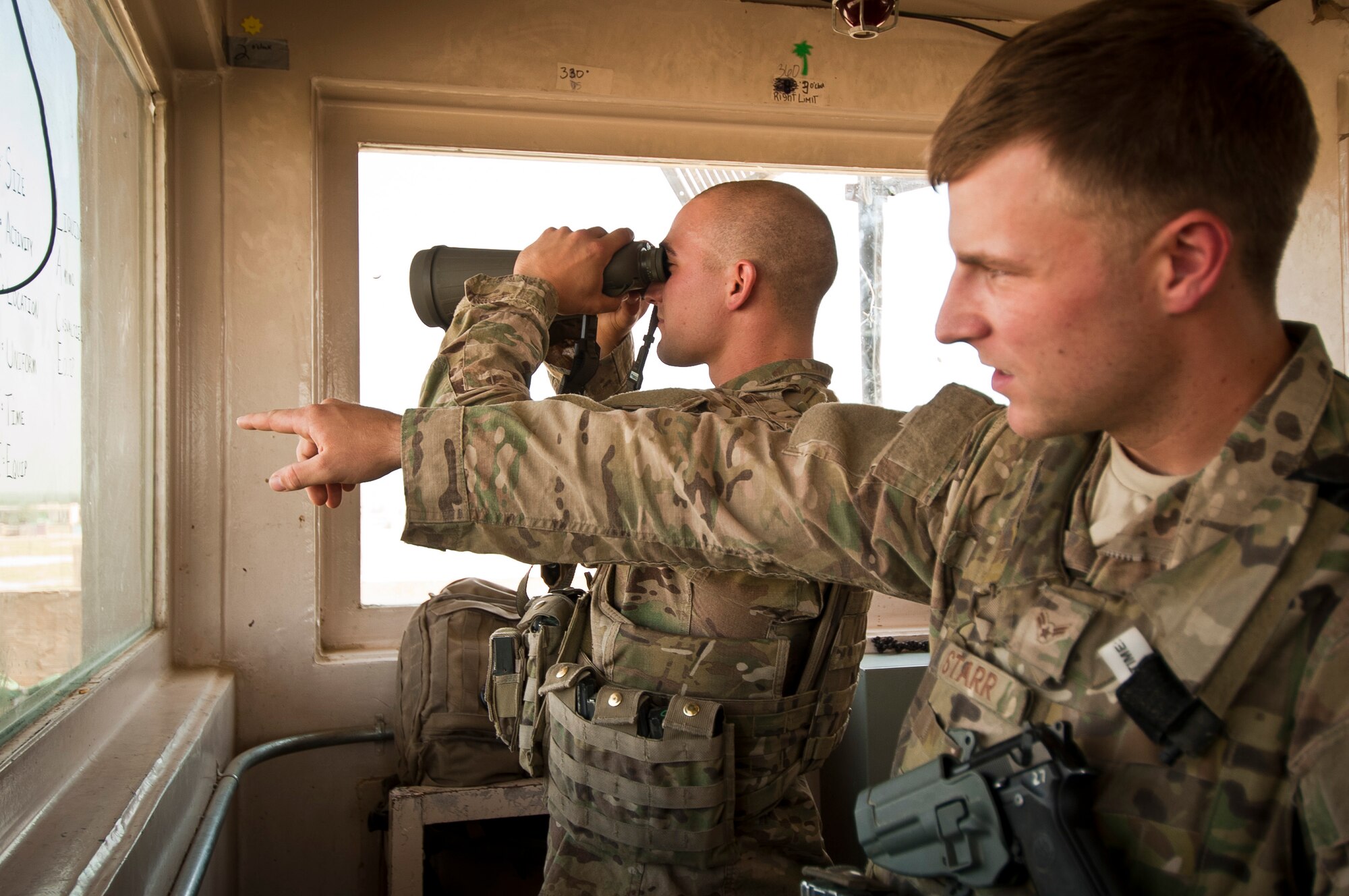 A1C Richard Starr, an Airman assigned to the 455th Expeditionary Security Forces Squadron, points out an item of interest to A1C Kory Caldwell, an Airman also deployed with 455 ESFS, while monitoring an  entry control point at Bagram Airfield Afghanistan, Aug. 18, 2012. Hundreds of Security Forces Airmen keep a constant vigil on Bagram, ready to deter, engage and defeat any potential threats. (U.S. Air Force Photo/Capt. Raymond Geoffroy)