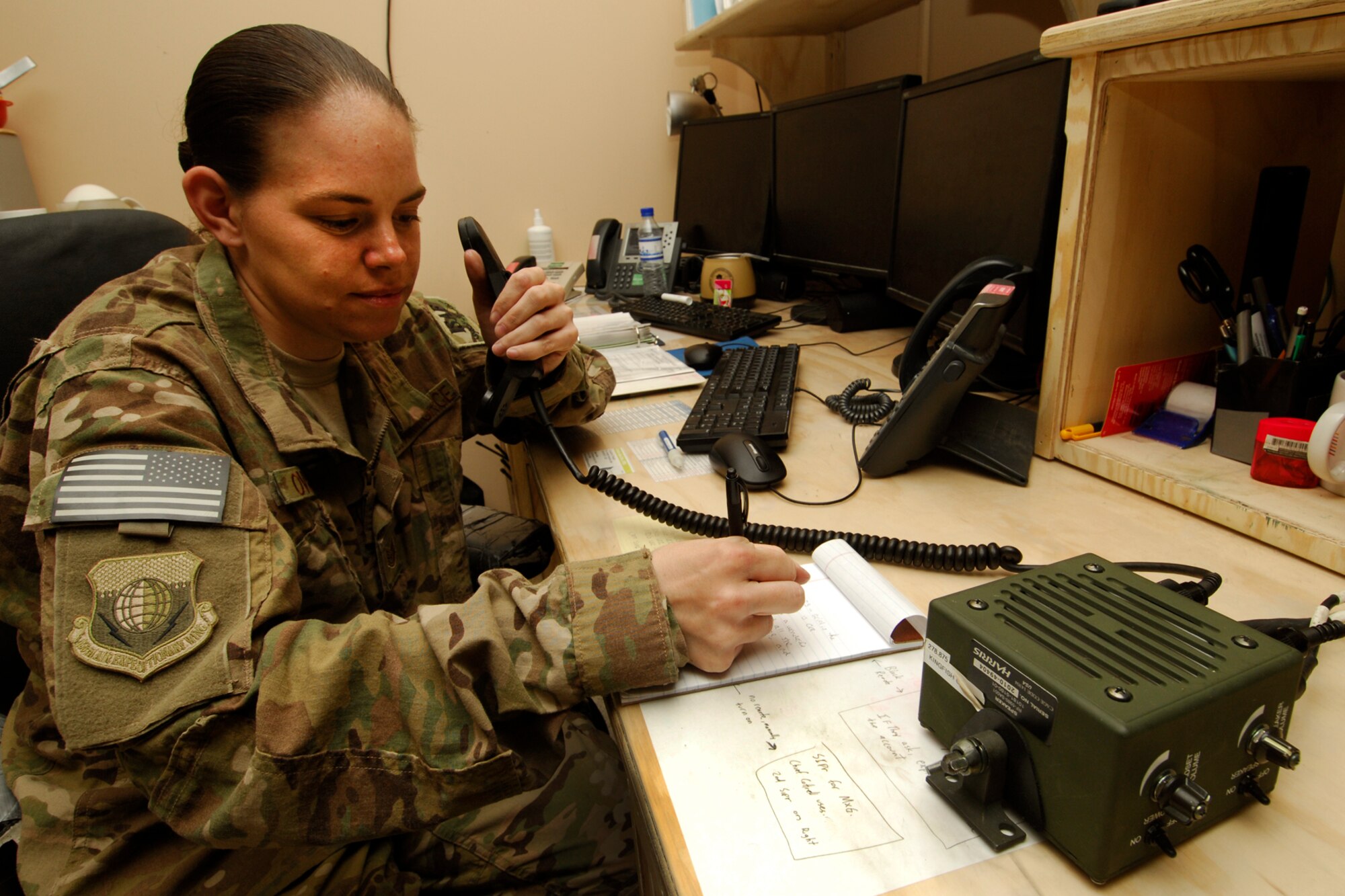 TSgt Kimberley Overturf, 455th Air Expeditionary Wing Command Post NCOIC of Console Operations, talks to an inbound aircraft on a radio while copying information being given to her so she can pass info to the wing’s support agencies. Overturf is responsible for maintaining the 455 AEW wing commander’s command and control node.  Additionally, TSgt Overturf is accountable for the immediate receipt and dissemination of the wing commander’s notifications and higher headquarters reporting.  (U.S. Air Force photos/SSgt Jeff Nevison)