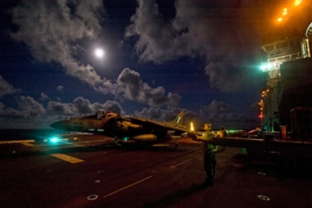 U.S. Navy flight deck personnel taxi an AV-8B Harrier jet aircraft assigned to Marine Attack Squadron 542 across the flight deck during night flight operations aboard the amphibious assault ship USS Bonhomme Richard under way in the Philippine Sea, Aug. 29, 2012. The Bonhomme Richard is the lead ship of the only forward-deployed amphibious assault group.