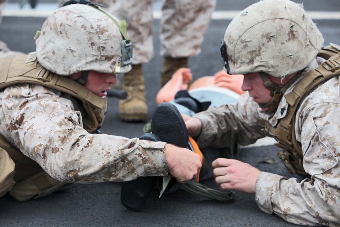 Corporal Michael C. Hartwig (left), motor transportation operator and Cpl. Jacob A. Johnson, motor transportation licensing non-commissioned officer in charge, both with Headquarters and Support Company, Battalion Landing Team 3/5, 15th Marine Expeditionary Unit, apply a splint to a simulated casualty during a Combat Life-saving Skills course aboard the USS Rushmore, Aug. 24. Hartwig ,24, is from Fort Atkinson, Wis,. and Johnson, 25, is from Coalville, Ill.