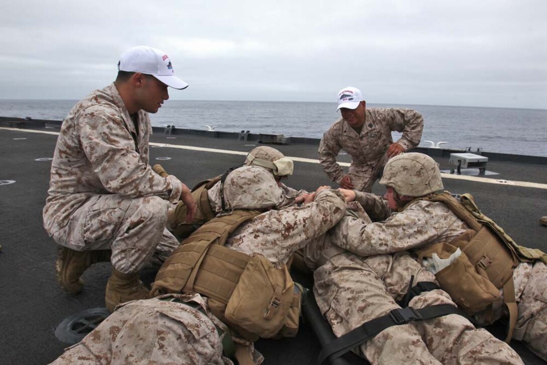 Corpsmen evaluate Marines from the 15th Marine Expeditionary Unit who are treating a simulated casualty during a Combat Life-saving Skills course aboard the USS Rushmore, Aug. 24. The four-day course teaches service members the basic level of Tactical Combat Casualty Care in order to stabilize casualties on the battlefield.