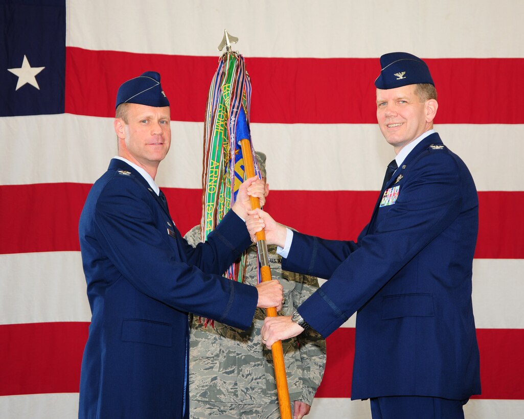 Col. James Sears, 14th Flying Training Wing Commander, passes the 14th Operations Group guidon to Col. Brett Pennington, 14th Operations Group Commander during the change of command ceremony on Aug. 23 at the Fuel Cell Maintenance Hangar. Prior to his current assignment Pennington was the Deputy Commander, 100th Operations Group, RAF Mildenhall, England. (U.S. Air Force photo/Melissa Doublin)