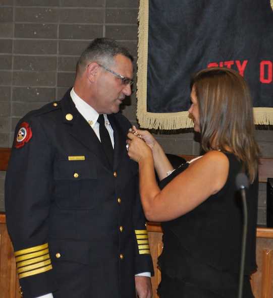 TRAVIS AIR FORCE BASE, Calif. --Frank Drayton's wife, Kim, pins his new badge to his uniform after he was sworn in Aug. 16, as the new Fire Chief for the City of Vacaville. It was standing room only in the city council chambers as family, friends and fellow fire personnel celebrated with Drayton. To the 349th Air Mobility Wing, he is Tech. Sgt. Drayton, and a long time fire fighter with the civil engineer squadron at Travis. (U.S. Air Force photo/Senior Master Sgt. Ellen Hatfield)