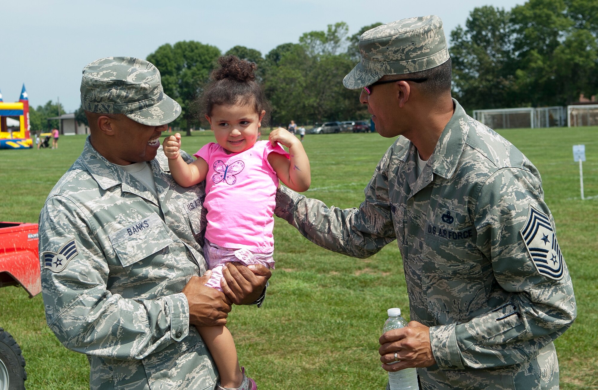 Chief Master Sgt. Terrence Greene, 87th Air Base Wing command chief, greets Madison, 2, and her father Senior Airman Alexandro Banks at the Joint Base McGuire-Dix-Lakehurst Annual Summer Picnic Aug. 24 held on Doughboy Field. Banks is an 87th ABW protocol specialist. Greene assisted in directing attendees through the lines for food and drink where the other chief master sergeants and first sergeants served hungry patrons. (U.S. Air Force photo by Wayne Russell/Released)