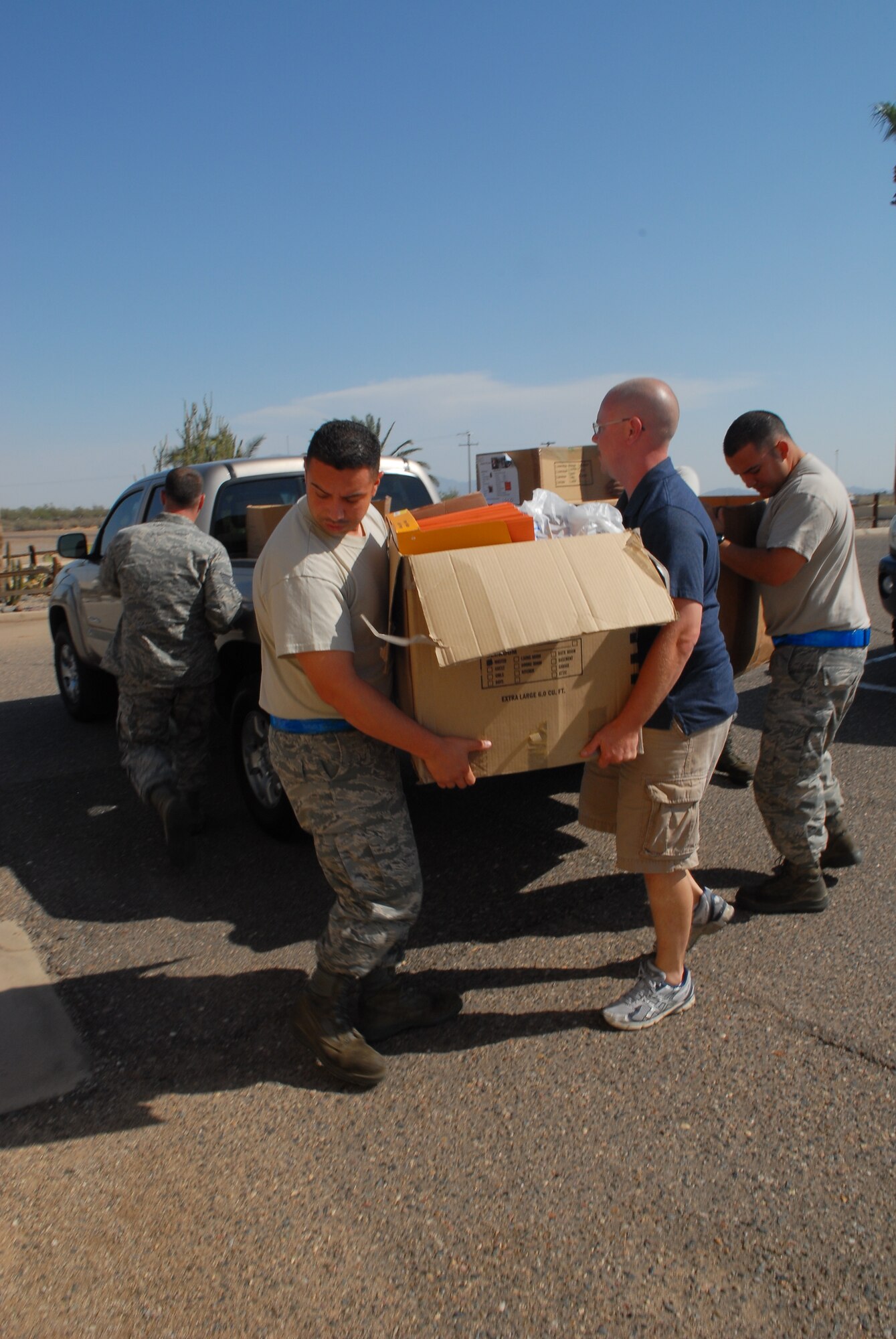 Tech. Sgt. Lisandro Delgado and Master Sgt. Austin English, 56th Component Maintenance Squadron test cell assistant section chief and section chief, unload a box of school supplies Aug. 14 at Bldg. 1010 on Luke Air Force Base.  The school supplies will be donated to Backpacks of Love, a program that provides school supplies to children who are victims of domestic violence.  (U.S. Air Force photo by Airman 1st Class Grace Lee)